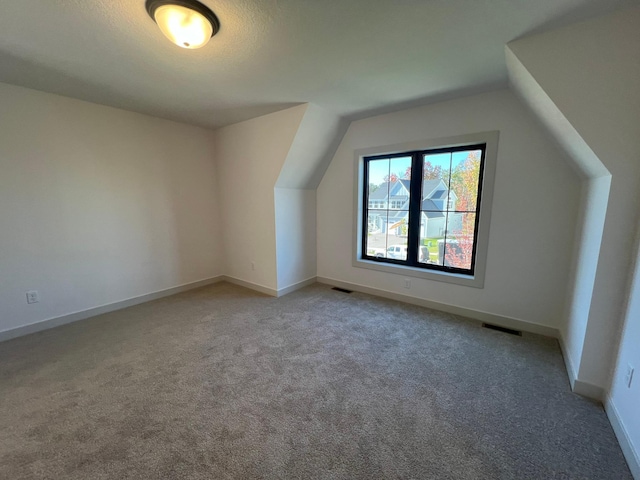 bonus room with vaulted ceiling and carpet