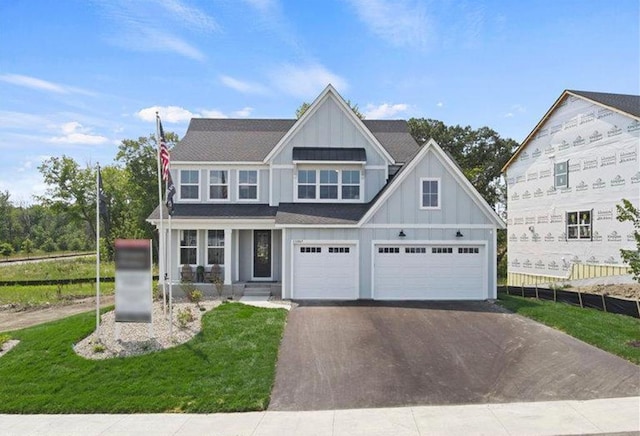 view of front of house featuring board and batten siding, fence, an attached garage, and aphalt driveway