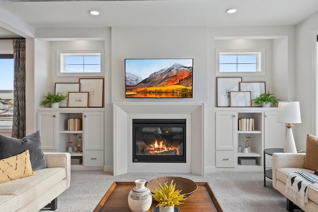 carpeted living area featuring recessed lighting, built in shelves, and a glass covered fireplace