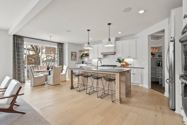 kitchen with tasteful backsplash, light wood finished floors, white cabinetry, and a kitchen breakfast bar