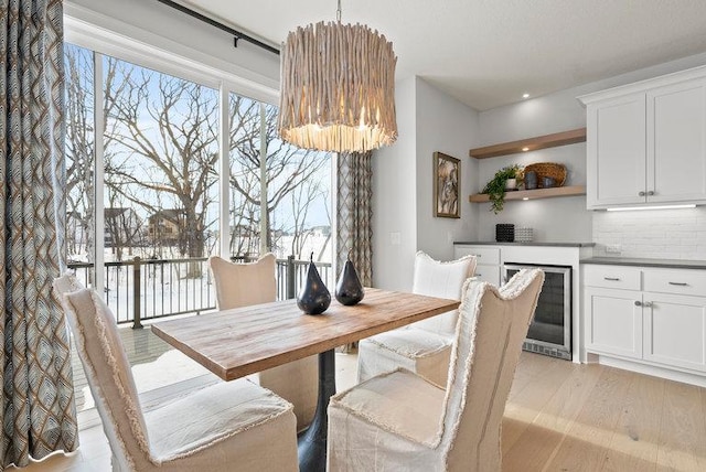 dining area with light wood finished floors, wine cooler, and a healthy amount of sunlight