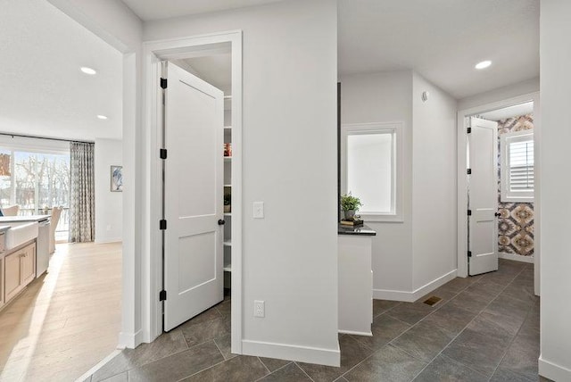 hall featuring baseboards, visible vents, a wealth of natural light, and recessed lighting