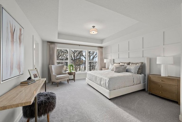 carpeted bedroom featuring a textured ceiling and a raised ceiling