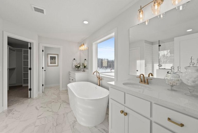 full bath with vanity, visible vents, a freestanding bath, marble finish floor, and a walk in closet