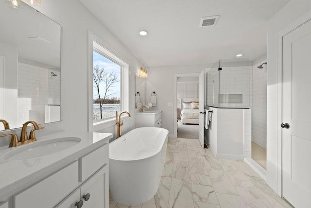 ensuite bathroom with marble finish floor, visible vents, a freestanding bath, vanity, and tiled shower