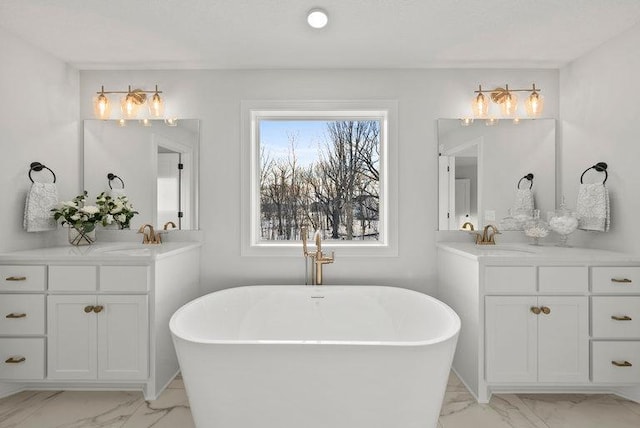 bathroom with a freestanding bath, marble finish floor, two vanities, and a sink