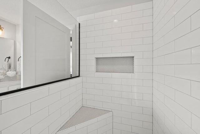 full bath featuring a textured ceiling and tiled shower