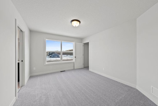 unfurnished bedroom with light carpet, visible vents, baseboards, and a textured ceiling