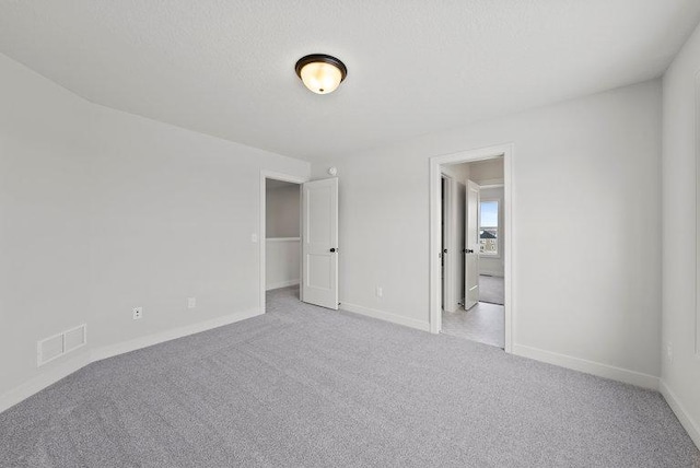 unfurnished bedroom with carpet flooring, visible vents, baseboards, and a textured ceiling