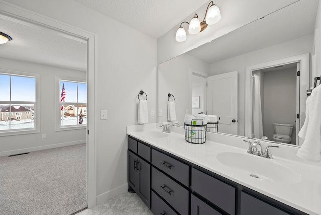 bathroom featuring double vanity, a textured ceiling, baseboards, and a sink