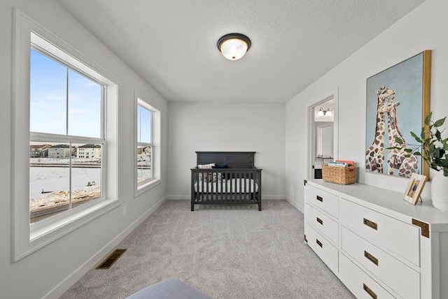 bedroom featuring light carpet, baseboards, visible vents, and a textured ceiling