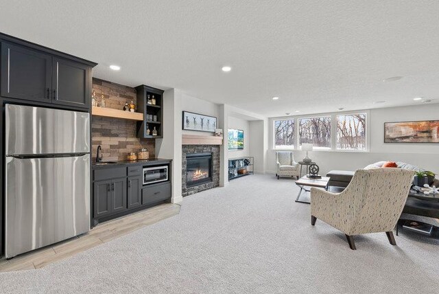 living room with light carpet, a fireplace, a textured ceiling, and recessed lighting