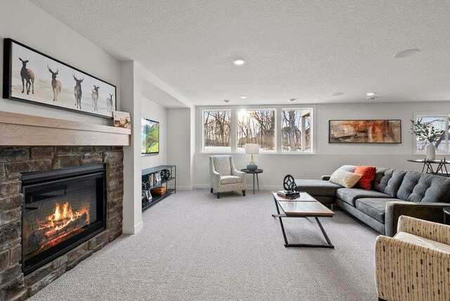 living area featuring baseboards, carpet, a textured ceiling, a fireplace, and recessed lighting