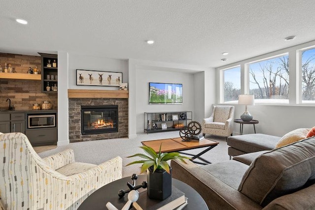 living area with carpet floors, wet bar, a stone fireplace, and a textured ceiling