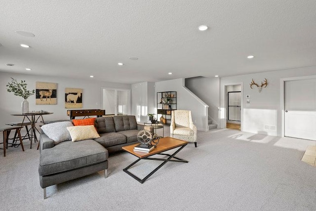 living room with light carpet, stairs, and a textured ceiling