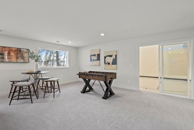 recreation room with a textured ceiling, carpet flooring, and baseboards