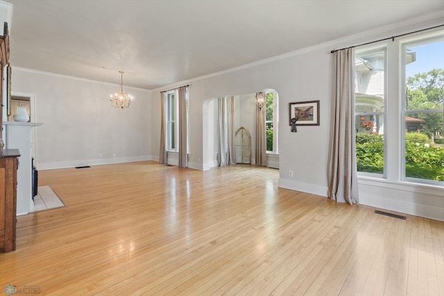 unfurnished living room with a notable chandelier, crown molding, and light wood-type flooring