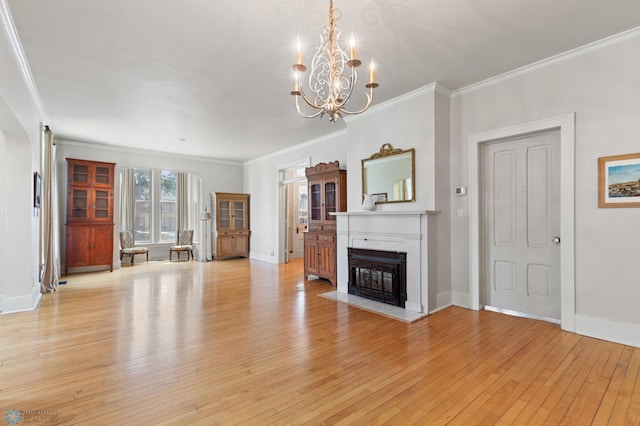 unfurnished living room with crown molding, an inviting chandelier, and light hardwood / wood-style floors