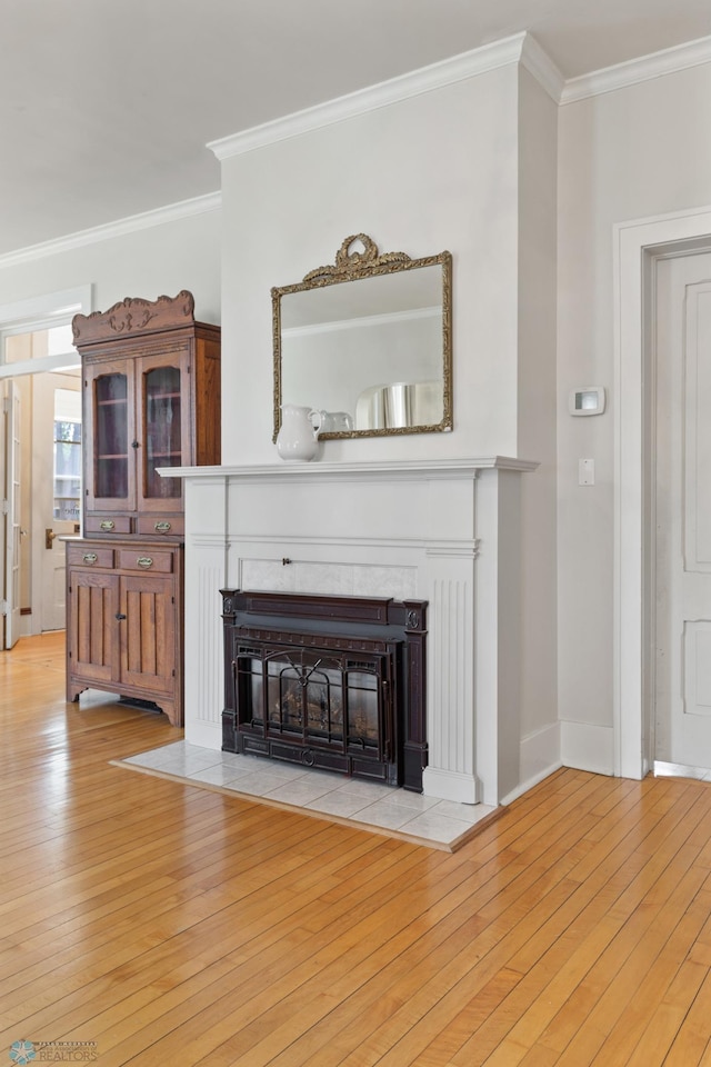 unfurnished living room featuring crown molding, a fireplace, and light wood-type flooring