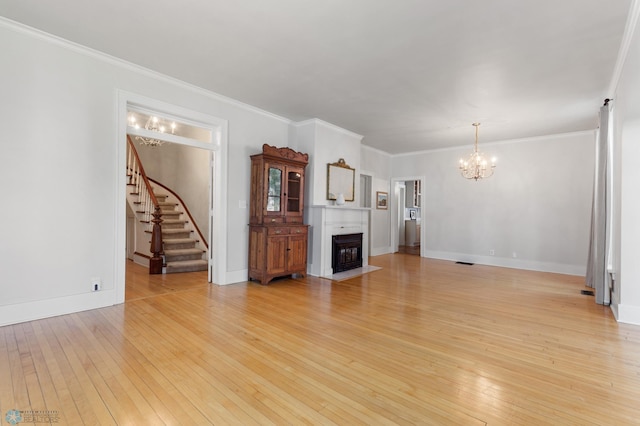 unfurnished living room with crown molding, an inviting chandelier, and light hardwood / wood-style flooring