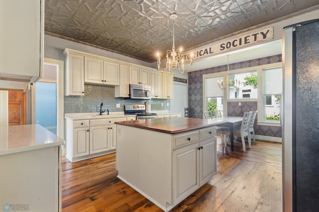 kitchen with a chandelier, a center island, hanging light fixtures, light hardwood / wood-style flooring, and appliances with stainless steel finishes