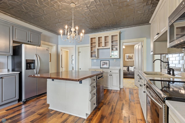 kitchen featuring gray cabinets, pendant lighting, sink, wooden counters, and stainless steel appliances