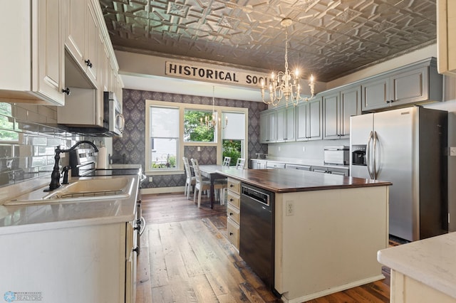 kitchen with butcher block counters, a chandelier, appliances with stainless steel finishes, a kitchen island, and pendant lighting