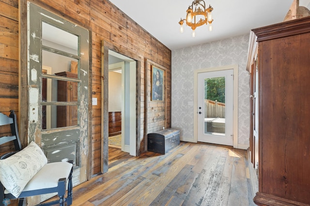 doorway with a notable chandelier and light wood-type flooring