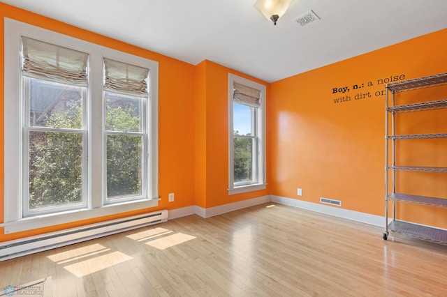 spare room with a baseboard radiator, light hardwood / wood-style flooring, and a wealth of natural light