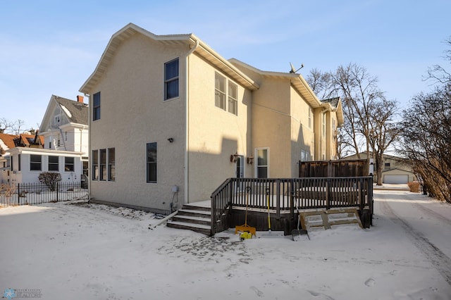 snow covered house featuring a garage and a deck