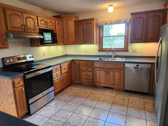 kitchen with a textured ceiling, light tile patterned flooring, sink, and stainless steel appliances