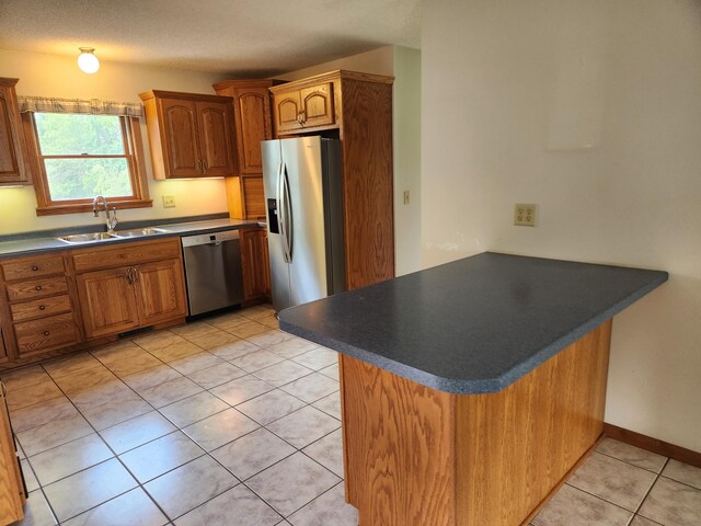 kitchen featuring light tile patterned floors, sink, kitchen peninsula, a textured ceiling, and stainless steel appliances