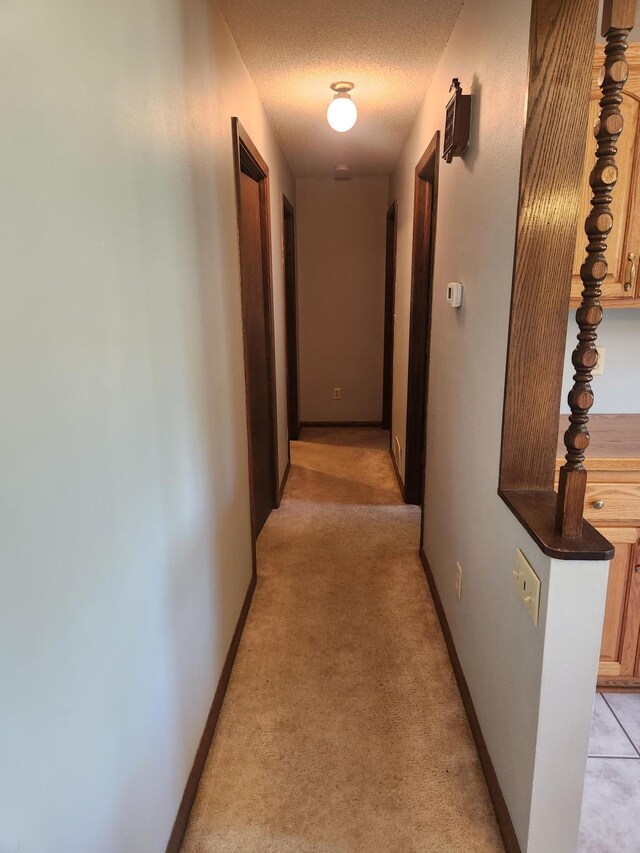 hallway with light carpet and a textured ceiling