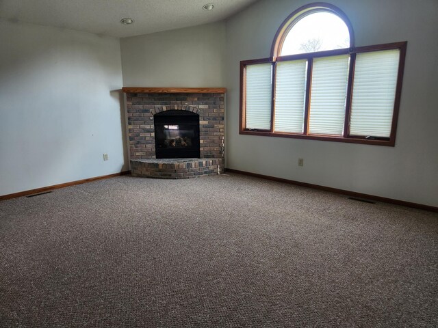 unfurnished living room featuring a textured ceiling, carpet flooring, lofted ceiling, and a brick fireplace