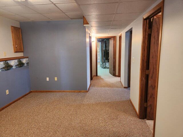 corridor featuring a paneled ceiling and light colored carpet