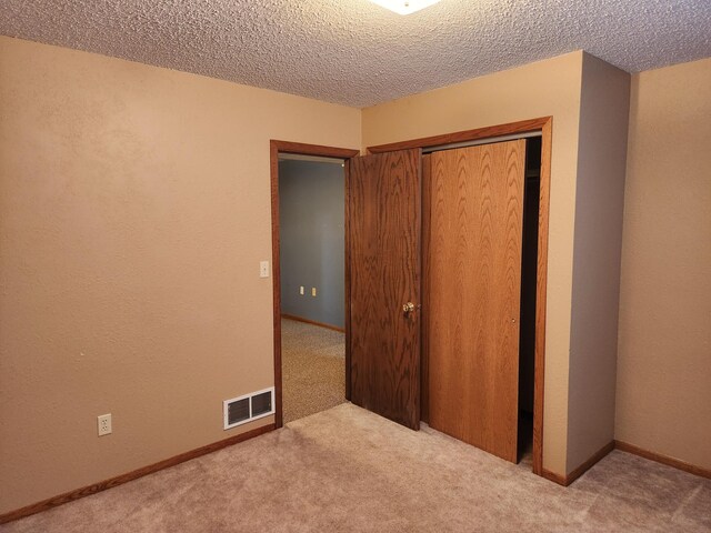 unfurnished bedroom featuring carpet, a closet, and a textured ceiling