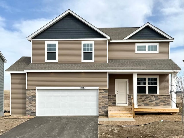 craftsman-style house with stone siding, covered porch, driveway, and a garage