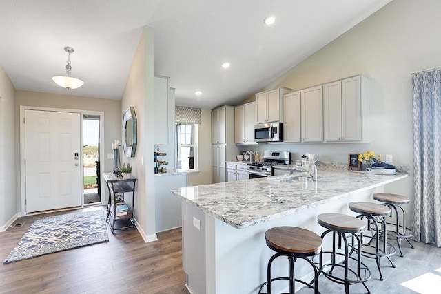 kitchen with appliances with stainless steel finishes, pendant lighting, sink, a breakfast bar area, and kitchen peninsula