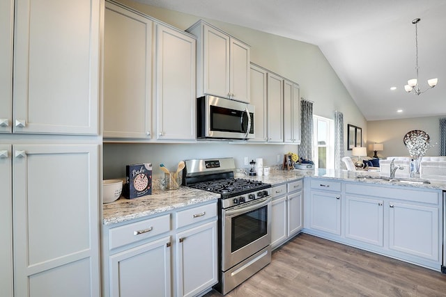 kitchen featuring sink, vaulted ceiling, appliances with stainless steel finishes, light hardwood / wood-style floors, and white cabinets