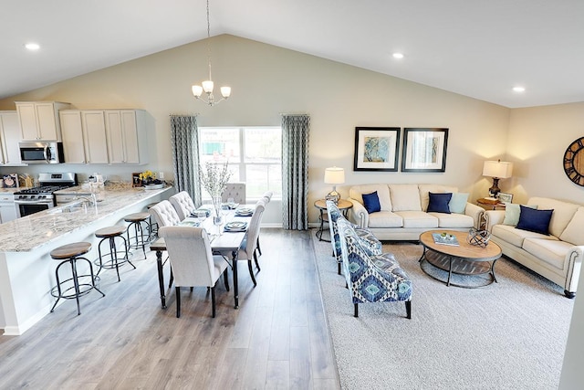 living room featuring high vaulted ceiling, a notable chandelier, and light wood-type flooring