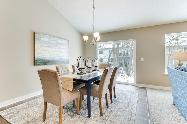 dining area featuring plenty of natural light, hardwood / wood-style floors, lofted ceiling, and an inviting chandelier