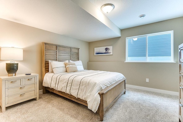 bedroom with baseboards, a textured ceiling, and light colored carpet