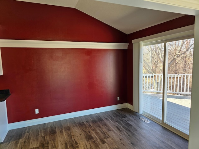 unfurnished room featuring lofted ceiling, visible vents, dark wood finished floors, and baseboards