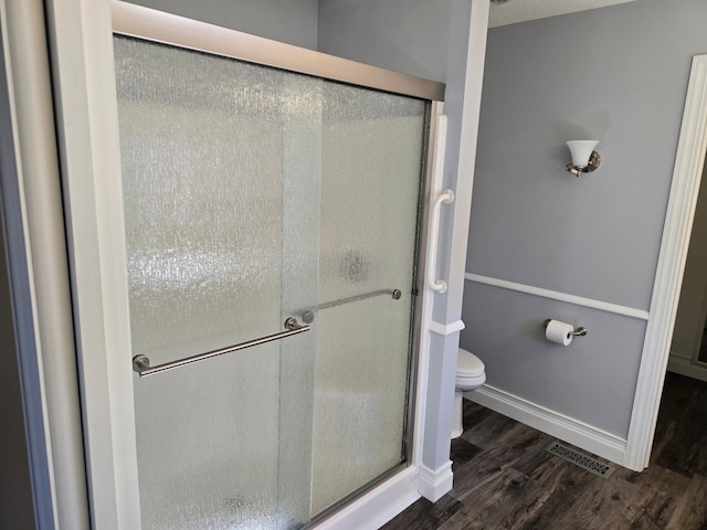 bathroom featuring visible vents, a shower stall, toilet, and wood finished floors