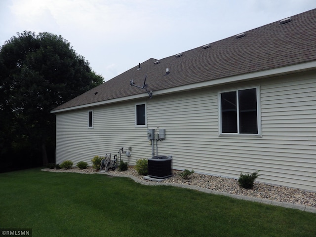 back of property with roof with shingles and a yard