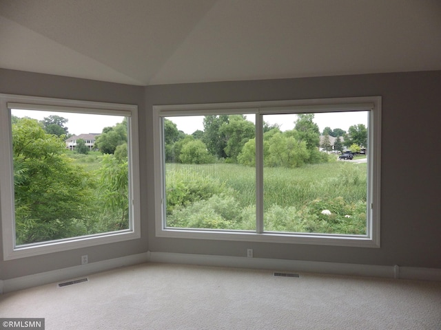 carpeted empty room with lofted ceiling, visible vents, and plenty of natural light