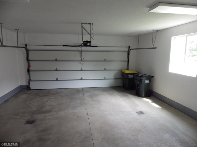 garage with a garage door opener, visible vents, and baseboards