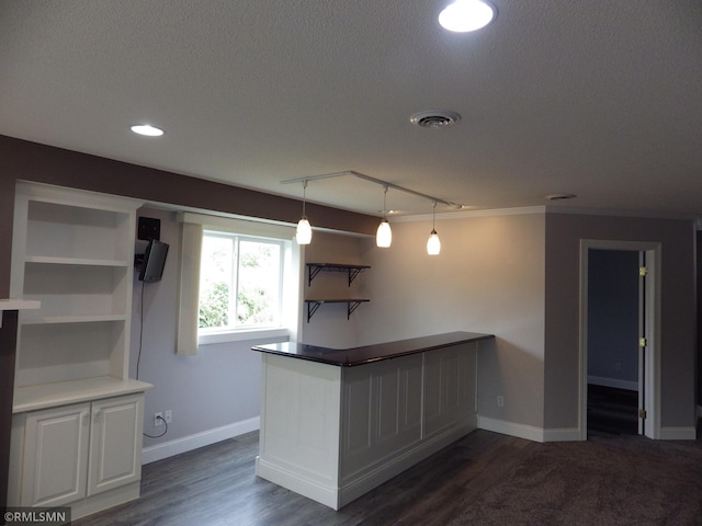 interior space featuring a textured ceiling, dark wood-type flooring, visible vents, baseboards, and open shelves