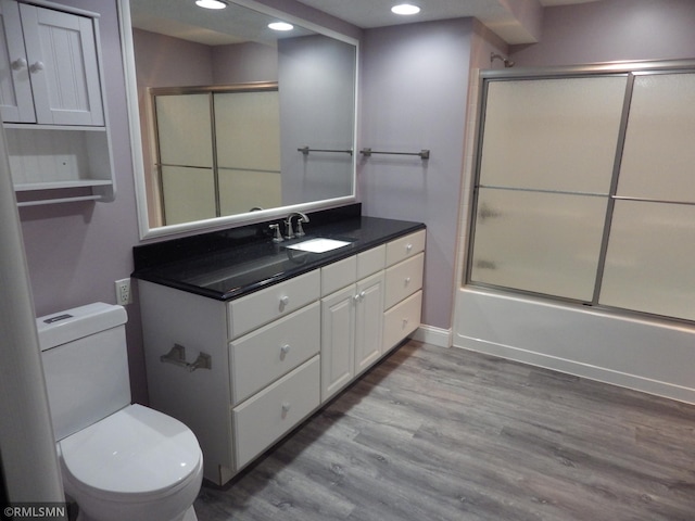 bathroom featuring shower / bath combination with glass door, recessed lighting, toilet, vanity, and wood finished floors