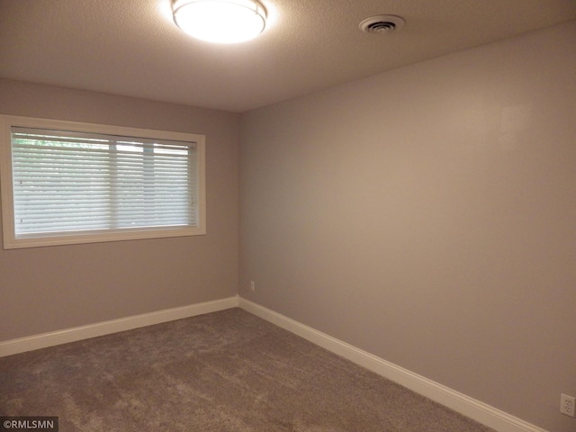 carpeted spare room featuring baseboards, visible vents, and a textured ceiling